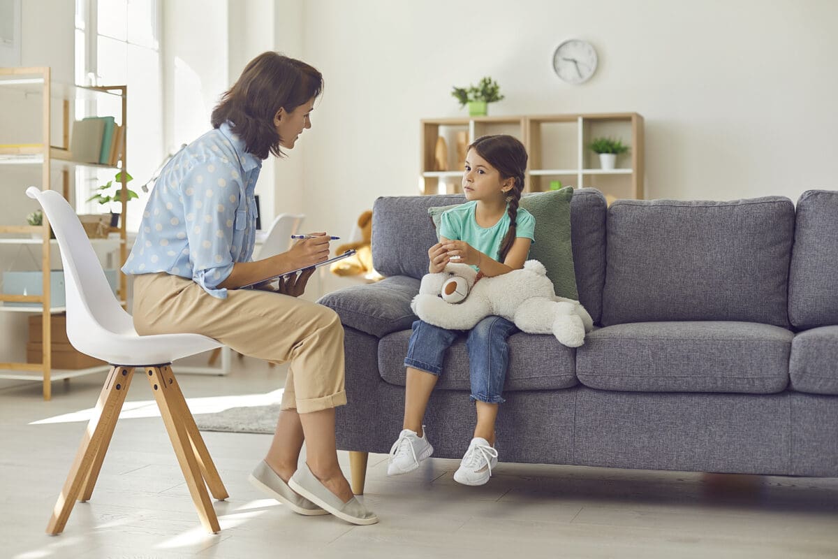 Female child psychologist working with a little preschool girl in a bright office.